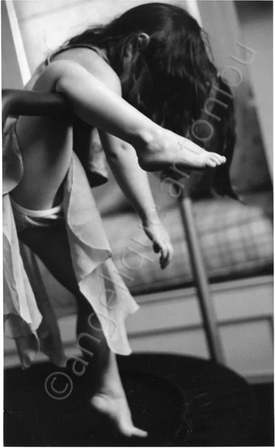 A young dancer folded forward over a barre, her hair falling towards the floor
